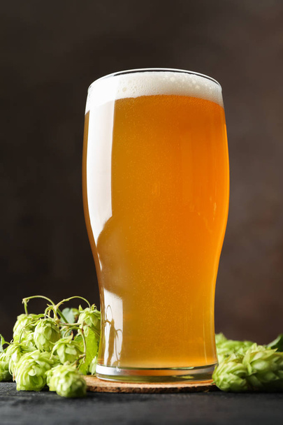 Glass of beer and hop cones on wooden table, copy space - 写真・画像