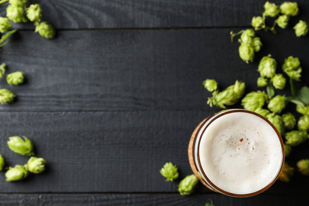 Ποτήρι μπύρας και κώνους λυκίσκου σε ξύλινο φόντο, κορυφή θέα - Φωτογραφία, εικόνα