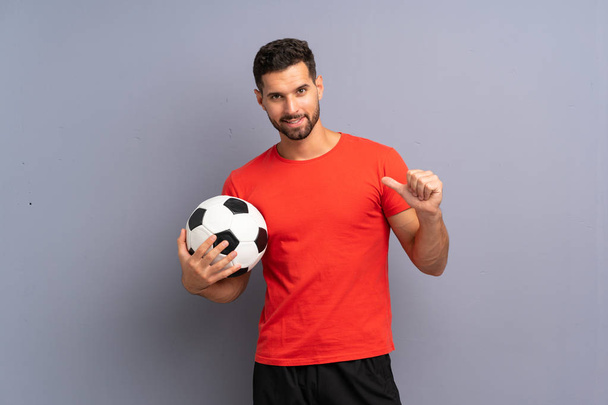 Handsome young football player man over isolated white wall proud and self-satisfied - Foto, imagen