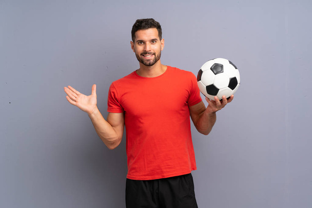 Guapo joven jugador de fútbol hombre sobre la pared blanca aislada con expresión facial impactada
 - Foto, imagen