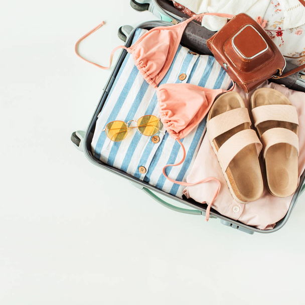 Reizen handbagage met badpak bikini, slippers, zonnebril, jurk, retro camera op witte achtergrond. Flat lay, Top uitzicht zomer vakantie concept. - Foto, afbeelding