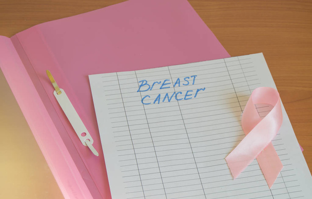 rosa Aktenordner mit Informationen zur Krebsvorbeugung. Brustkrebs-Bewusstsein mit rosa Schleife. - Foto, Bild