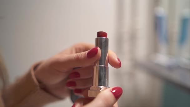 A young girl opens her red lipstick. - Video