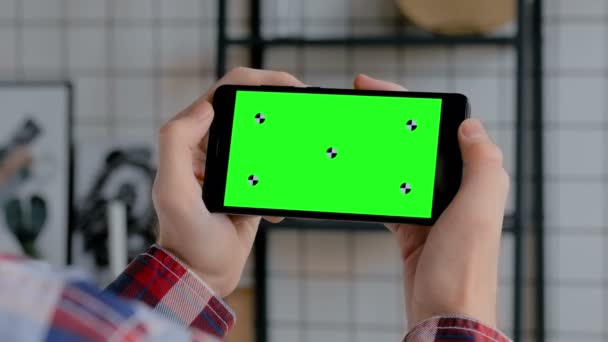 Mężczyzna trzyma czarny smartfon z pustym zielonym ekranem-koncepcja klucza Chroma - Materiał filmowy, wideo