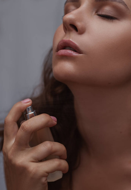 Close-up van een mooie vrouw toepassen van parfum  - Foto, afbeelding