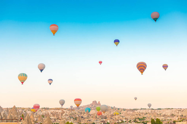 Colorful hot air balloons flying over at fairy chimneys in Nevsehir, Goreme, Cappadocia Turkey. Hot air balloon flight at spectacular Cappadocia Turkey. - Foto, afbeelding
