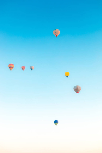 Πολύχρωμα μπαλόνια θερμού αέρα πετούν πάνω σε καπνοδόχους στην Νεβσεχίρ, Γκορέμε, Καππαδοκία Τουρκία. Πτήση με αερόστατο στην εντυπωσιακή Καππαδοκία Τουρκία. - Φωτογραφία, εικόνα
