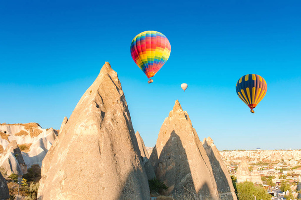 Πολύχρωμα μπαλόνια θερμού αέρα πετούν πάνω σε καπνοδόχους στην Νεβσεχίρ, Γκορέμε, Καππαδοκία Τουρκία. Πτήση με αερόστατο στην εντυπωσιακή Καππαδοκία Τουρκία. - Φωτογραφία, εικόνα