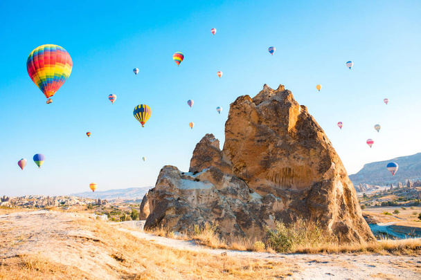 Красочные воздушные шары, летящие над сказочными дымоходами в Невшехире, Гореме, Каппадокии, Турции. Полет на воздушном шаре в Каппадокии
. - Фото, изображение