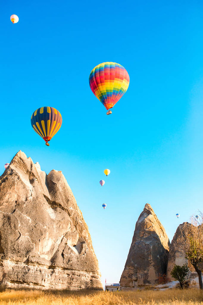 Colorful hot air balloons flying over at fairy chimneys in Nevsehir, Goreme, Cappadocia Turkey. Hot air balloon flight at spectacular Cappadocia Turkey. - Fotografie, Obrázek