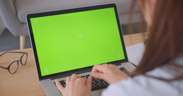 Closeup back view portrait of young caucasian female doctor using laptop with green chroma key screen indoors in office - Filmagem, Vídeo