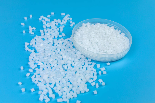 Transparante polypropyleen, polypropene, polystyreen, polyethyleen, thermoplastisch polymeer, HDPE en plastic grondstof pellets of korrels op geïsoleerde blauwe achtergrond - Foto, afbeelding