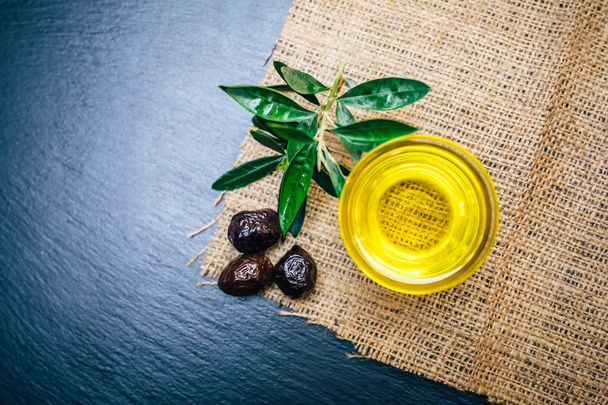 Aceite de oliva prensado en frío orgánico, natural y saludable sobre mesa de madera. Aceite de oliva virgen italiano o español en un bol para un desayuno vegetariano o vegano saludable close up concept image
. - Foto, Imagen