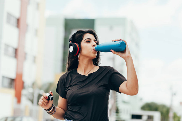 Beautiful young woman using headphone listening to music and dri - Фото, изображение