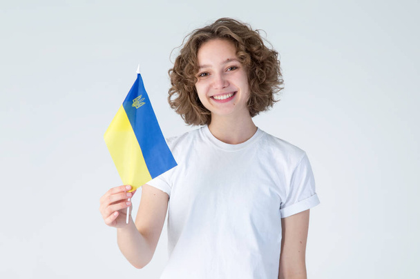 Happy young woman holding flag of Ukraine, on the white background. - Foto, Imagem