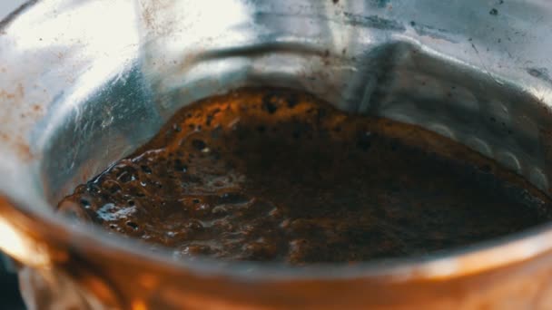 El café negro molido en un turco de cobre se prepara y hierve en una estufa de gas. Barista preparando caliente sabrosa bebida en casa de cerca
 - Metraje, vídeo