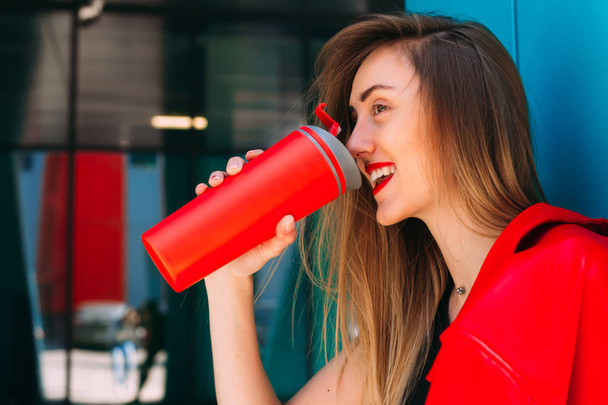 closeup του κοριτσιού σε κόκκινο δερμάτινο μπουφάν ποτά από κόκκινο θερμική mu - Φωτογραφία, εικόνα