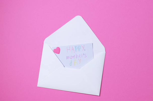 white envelope with a note inside I love mom on a pink background.For mom - Zdjęcie, obraz