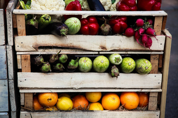 Verschillende soorten groenten en fruit gerangschikt in houten kisten, aanbod op de boerenmarkt - Foto, afbeelding
