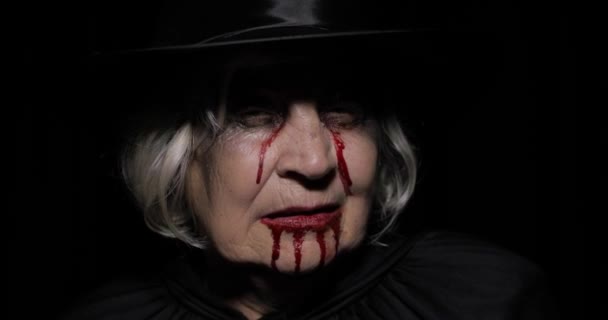 Old witch Halloween makeup. Elderly woman portrait with blood on her face. - Footage, Video