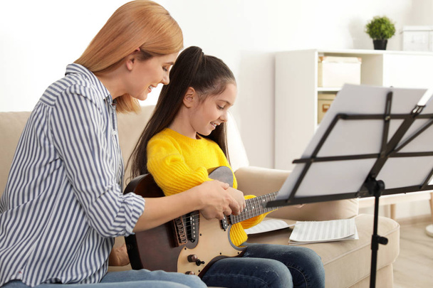 Bambina che suona la chitarra con il suo insegnante a lezione di musica. Note di apprendimento
 - Foto, immagini