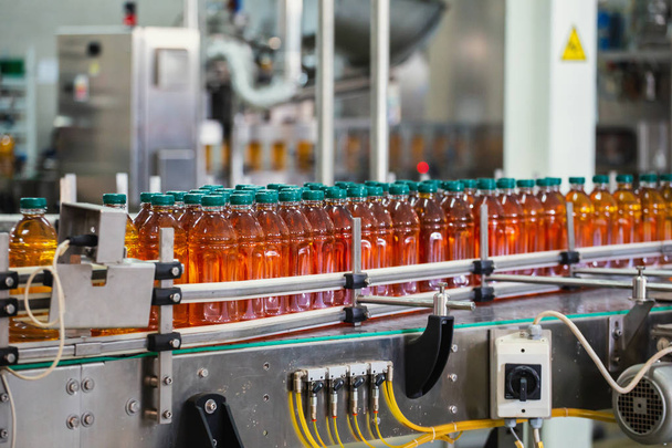 Linia przenośnika z plastikowymi butelkami soku w nowoczesnym sprzęcie fabrycznym. Wnętrze fabryki napojów wewnątrz - Zdjęcie, obraz