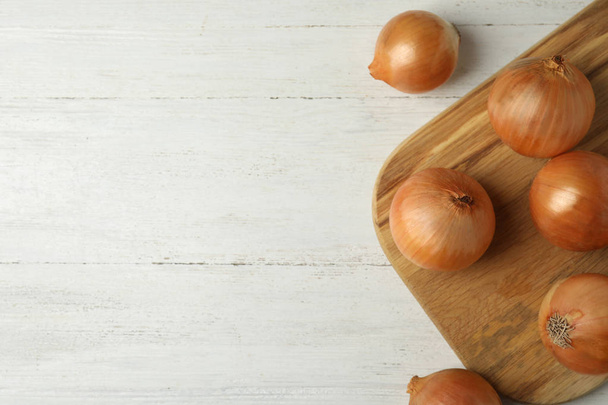 Ripe onions on white wooden table, flat lay with space for text - Photo, image