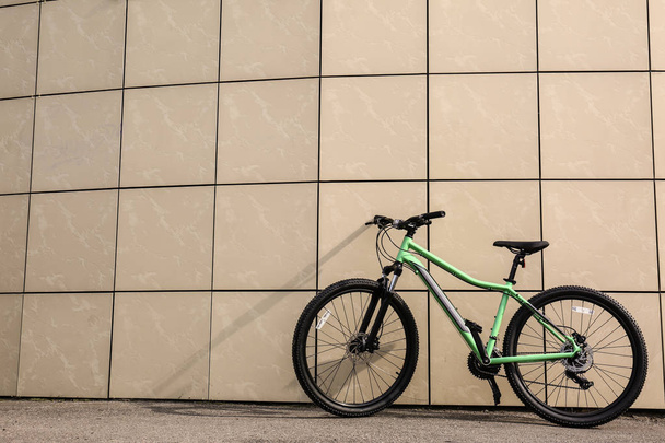 Modern bicycle near beige wall outdoors. Space for text - 写真・画像