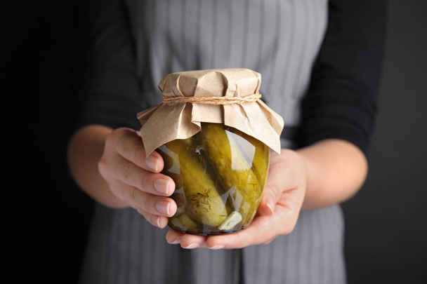 Woman holding jar of pickled cucumbers, closeup view - Фото, изображение