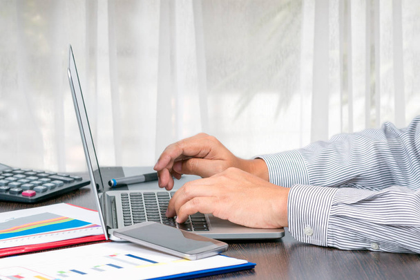 Een zakenman te typen om de gegevens van de verkoopvolume rapport van laptop in woonkamer te controleren - Foto, afbeelding