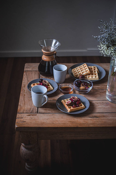 Κολοράντο, Ηνωμένες Πολιτείες. 2019 Αυγούστου. Καφετιέρα Chemex στο ξύλινο τραπέζι πρωινού με βάφλες, καφέ και λουλούδια. - Φωτογραφία, εικόνα