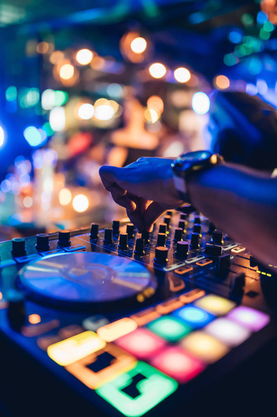 DJ suona dal vivo e mixa musica sulla console del giradischi sul palco del night club. Disco Jokey Mani su una stazione di mixer audio alla festa del club. Pannello controller mixer DJ per riprodurre musica e feste. - Foto, immagini