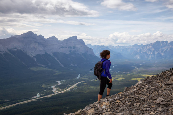 Adventurous Girl is hiking up a rocky mountain during a cloudy and rainy day. Taken from Mt Lady MacDonald, Canmore, Alberta, Canada. - Foto, imagen