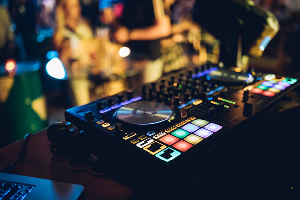 DJはナイトクラブのステージでターンテーブルコンソールでライブセットとミキシング音楽を演奏します。ディスクジョッキークラブパーティーでサウンドミキサーステーションに手。音楽やパーティーを再生するためのDJミキサーコントローラーパネル. - 写真・画像