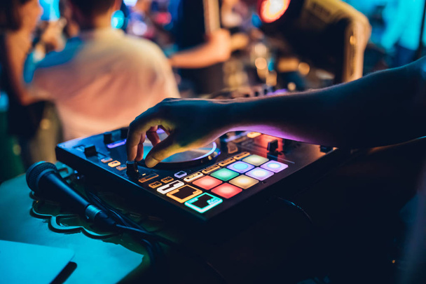 DJ plays live set and mixing music on turntable console at stage in the night club. Disc Jokey Hands on a sound mixer station at club party. DJ mixer controller panel for playing music and partying. - Photo, Image