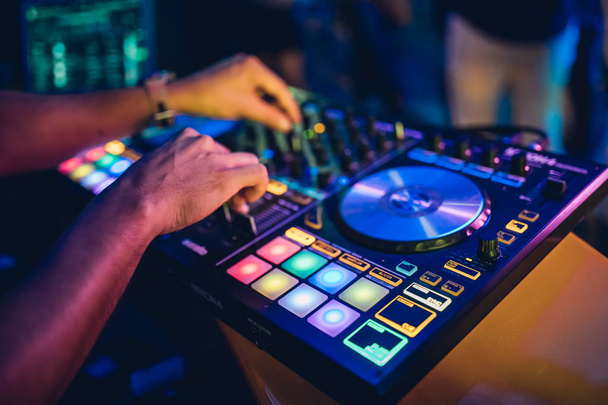 Ο DJ παίζει live set και αναμιγνύει μουσική σε πικάπ στη σκηνή του night club. Disc Jokey χέρια σε ένα σταθμό μίξερ ήχου στο κόμμα club. DJ πίνακα ελέγχου μίξερ για αναπαραγωγή μουσικής και πάρτι. - Φωτογραφία, εικόνα