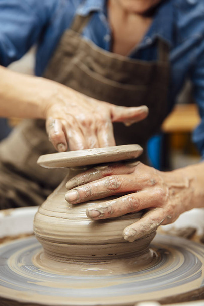 Mains de potière senior travaillant sur la roue de poterie alors qu'elle était assise dans son atelier
 - Photo, image