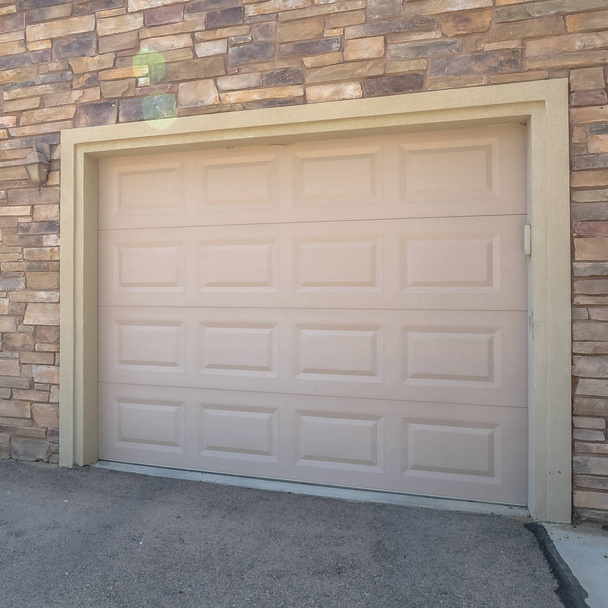 Portas brancas quadradas da garagem de uma casa contra a parede exterior coberta com tijolos de pedra
 - Foto, Imagem