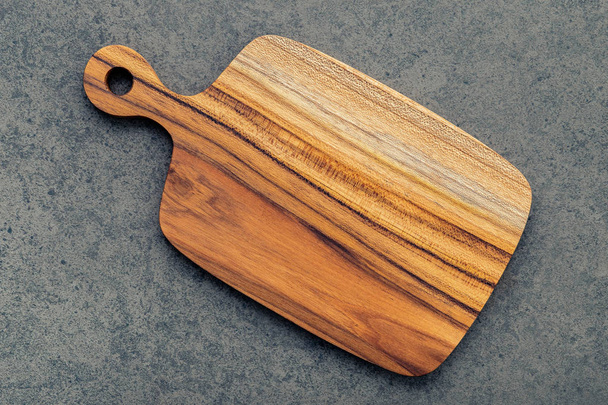 Chopping teak wood cutting board on dark stone background. - Photo, Image