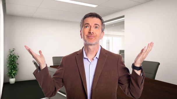 Middle-Aged businessman with gray hair and wearing a brown jacket standing in an office.  Depicts startup and corporate business.  He is advertising or presenting something. - Photo, Image