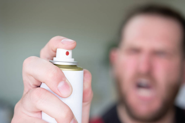 a middle-aged man violently holds an aerosol to kill insects - Foto, afbeelding
