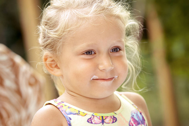 Cute little girl child with traces of ice cream on her face on a - Photo, Image