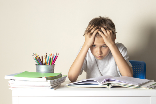 Втомився засмучений школяр з купою шкільних книг і блокнотів
 - Фото, зображення