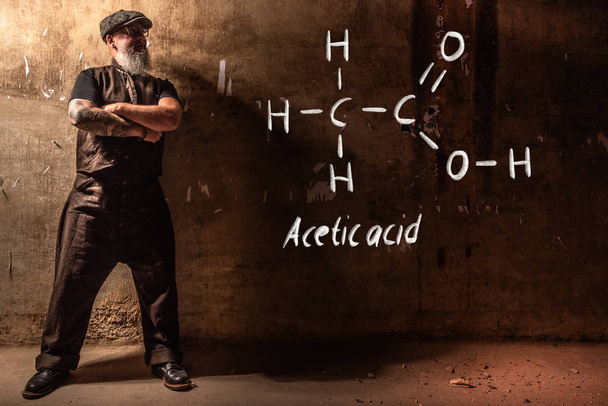 Homem velho barbudo apresentando fórmula química desenhada à mão de ácido acético CH3COOH
 - Foto, Imagem