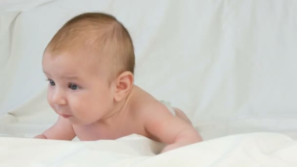 Retrato de hermoso bebé recién nacido divertido de dos meses acostado en la cama blanca
 - Metraje, vídeo