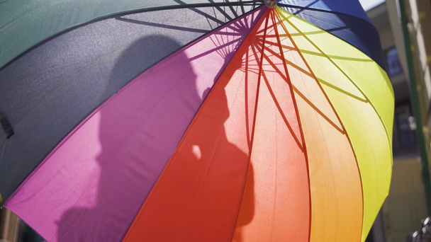 La mujer escondida detrás de un paraguas multicolor de pie en la calle. Chica irreconocible disfrutando de un día soleado en la vieja ciudad europea. Estilo de vida feliz
 - Imágenes, Vídeo