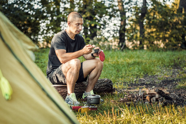 Tourist eats food in the summer forest. Outdoor recreation. - Photo, Image