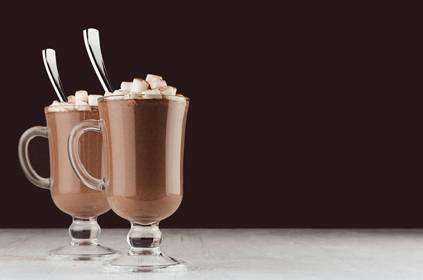 Elegant hot chocolate in two glass with marshmallows and silver spoon on dark brown background, copy space. - Fotoğraf, Görsel