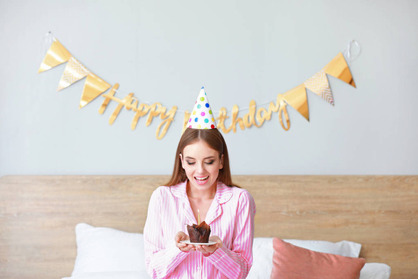 Femme heureuse avec gâteau d'anniversaire dans la chambre à coucher à la maison
 - Photo, image
