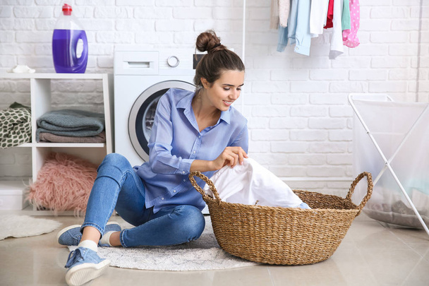 Beautiful young woman doing laundry at home - Фото, изображение